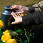 Hands,Touching,A,Burial,Urn,In,A,Bright,Outdoor,Funeral